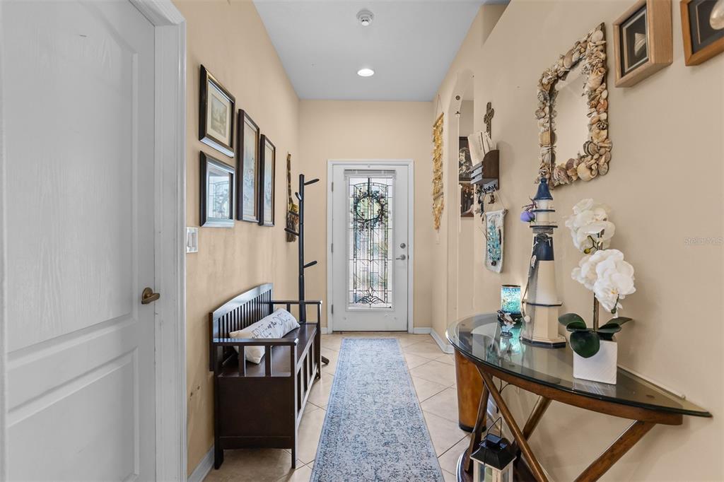 A tiled entryway features a wooden bench, a glass-topped console table, and a front door — 905 PARKER DEN DRIVE, RUSKIN, FL
