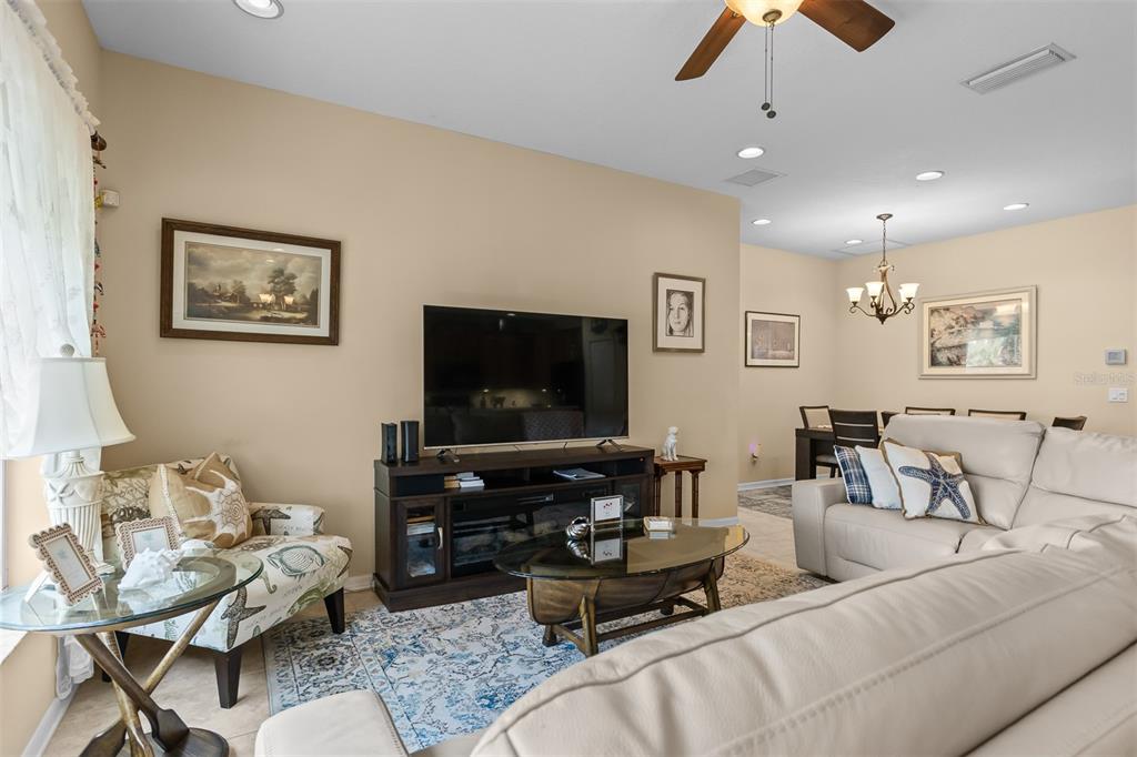 A living room features a television console, a patterned armchair, and a beige sectional sofa — 905 PARKER DEN DRIVE, RUSKIN, FL