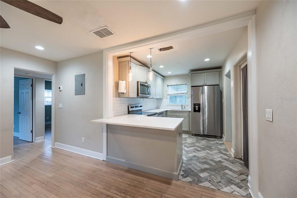 A kitchen with a breakfast bar, stainless steel appliances, and gray cabinets overlooks a room — 230 STRATHY LANE, WINTER PARK, FL