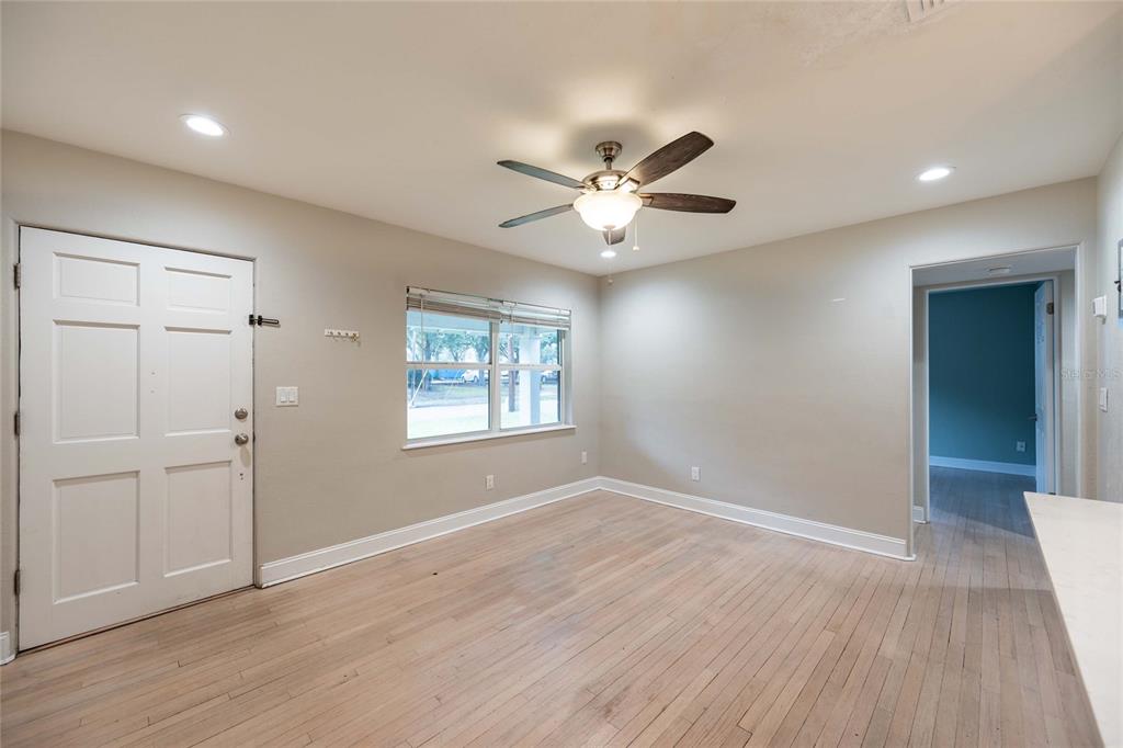 An empty room features light wood flooring, a ceiling fan, and a white entry door — 230 STRATHY LANE, WINTER PARK, FL