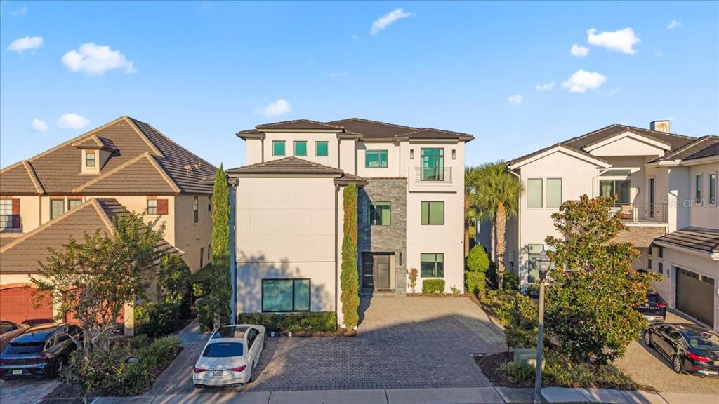 A three-story modern house with a stone facade and a paved driveway sits between neighbors — 331 MUIRFIELD LOOP, REUNION, FL
