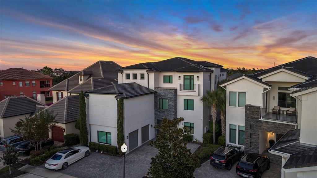 An aerial view of a modern multi-story house with a paved driveway at sunset — 331 MUIRFIELD LOOP, REUNION, FL