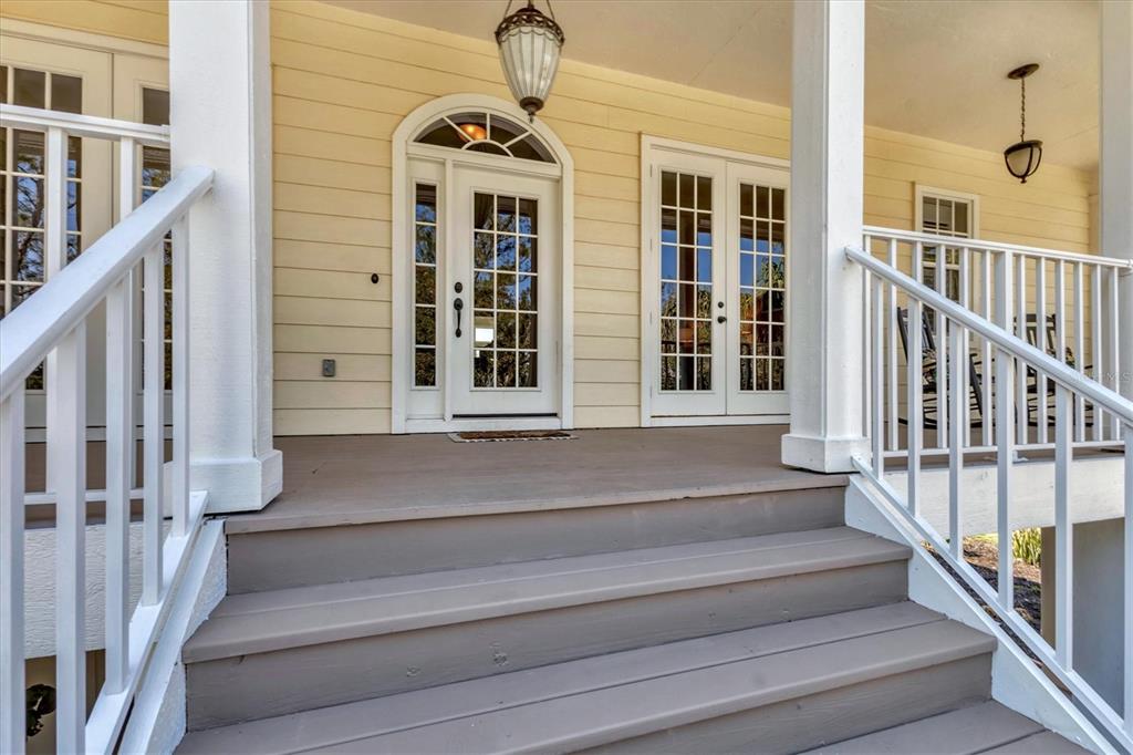 A wooden porch with white railings leads to a front door and French doors — 92 TIDY ISLAND BOULEVARD, BRADENTON, FL