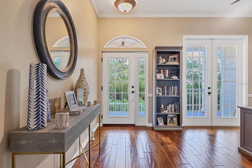 A foyer features hardwood floors, a console table, a bookshelf, and glass-paned exterior doors — 92 TIDY ISLAND BOULEVARD, BRADENTON, FL