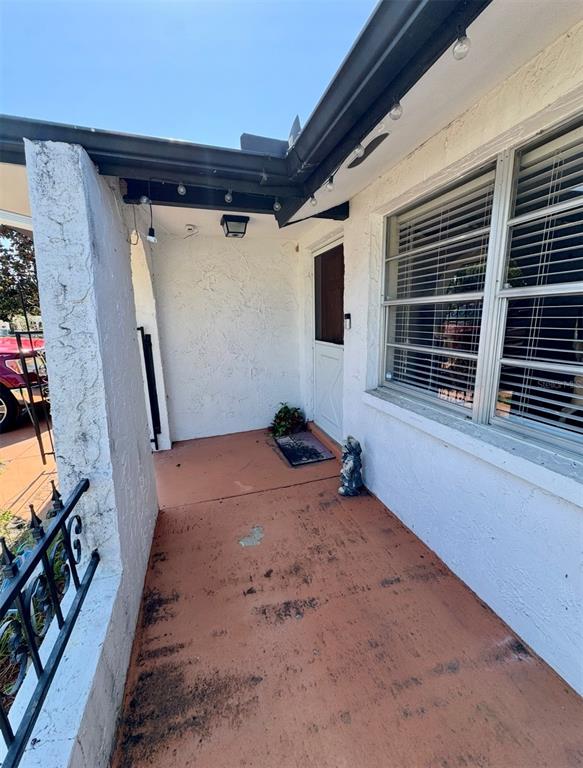 A covered front porch with a terracotta-colored concrete floor and a white exterior wall — 6432 JUNIPER ROAD, PORT RICHEY, FL