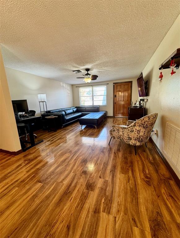A living room features hardwood floors, a black sectional sofa, and a patterned armchair — 6432 JUNIPER ROAD, PORT RICHEY, FL