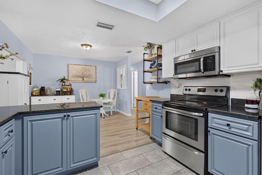 A single-story gray brick house with a cracked concrete driveway and large shade trees — 508 COCOPLUM DRIVE, SEFFNER, FL