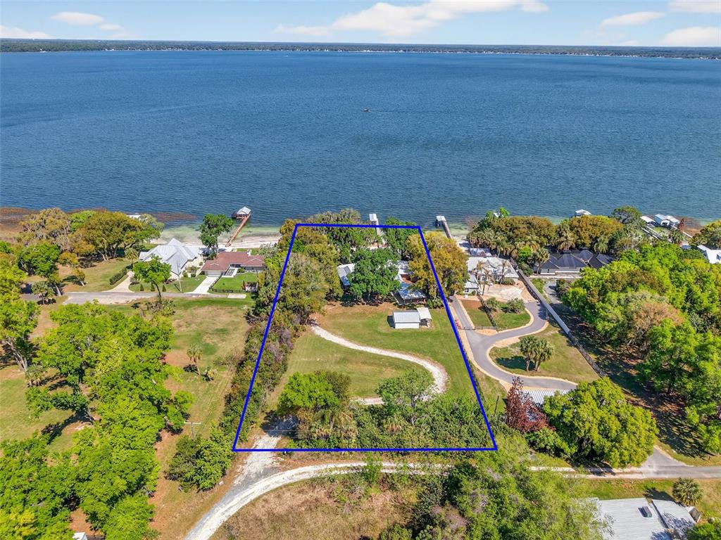 An aerial view shows a waterfront lot with a house, shed, and trees — 13033 SE 158TH LANE, WEIRSDALE, FL