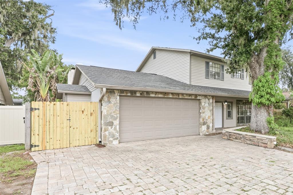 A two-story house with a stone-accented garage, a paved driveway, and a wooden fence — 1010 MALLOW WAY, BRANDON, FL