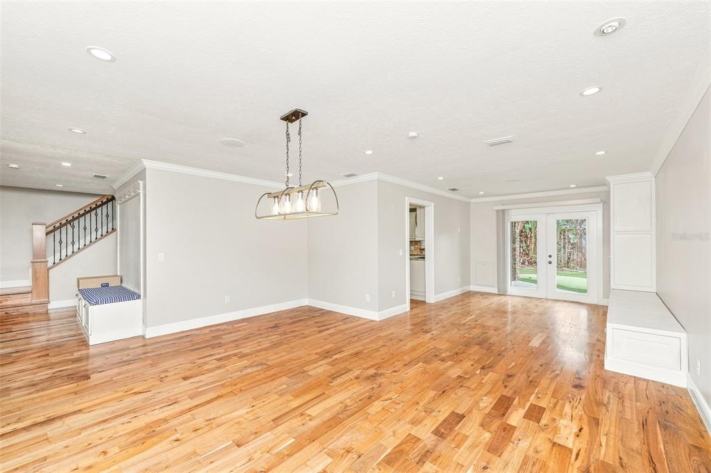 An open dining area features hardwood floors, a chandelier, built-in seating, and glass patio doors — 1010 MALLOW WAY, BRANDON, FL
