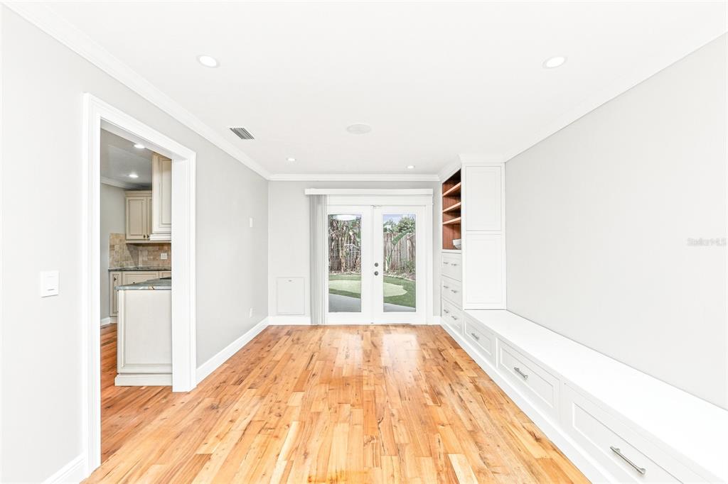 A dining room with hardwood floors, built-in cabinetry, and French doors leading to a backyard — 1010 MALLOW WAY, BRANDON, FL