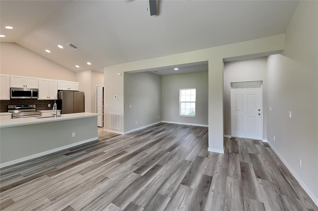 An open-concept kitchen and living area feature light gray walls and wood-look plank flooring — 8878 BESSEMER COURT, NORTH PORT, FL