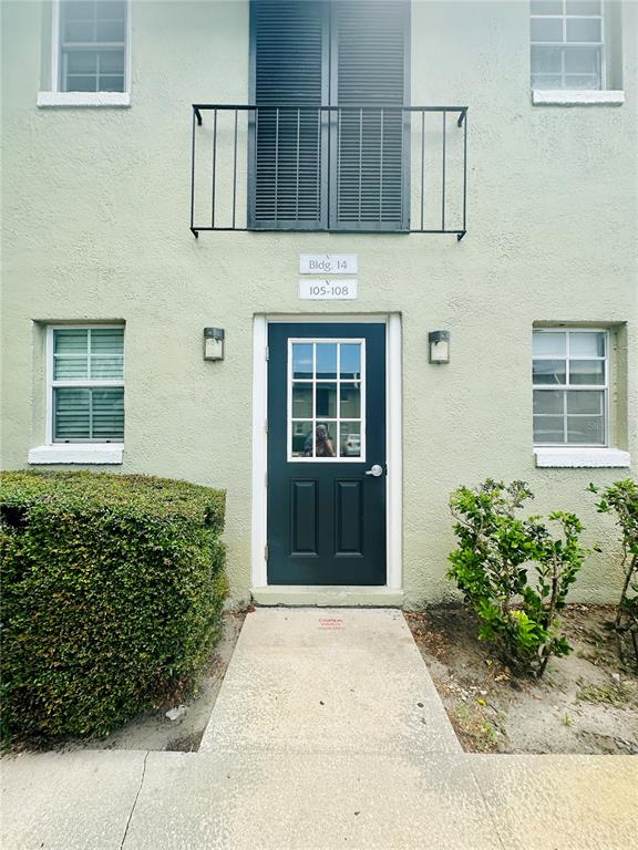 A staircase sits between two dark doors labeled 106 and 105 in a hallway — 525 CONWAY ROAD UNIT 108, ORLANDO, FL