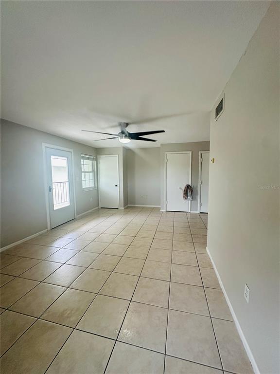 A room with light-colored tile flooring, a ceiling fan, and multiple white doors — 525 CONWAY ROAD UNIT 108, ORLANDO, FL