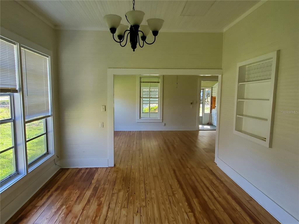 A dining room with hardwood floors, a chandelier, and a built-in wall shelf — 18670 NW 246TH STREET, HIGH SPRINGS, FL
