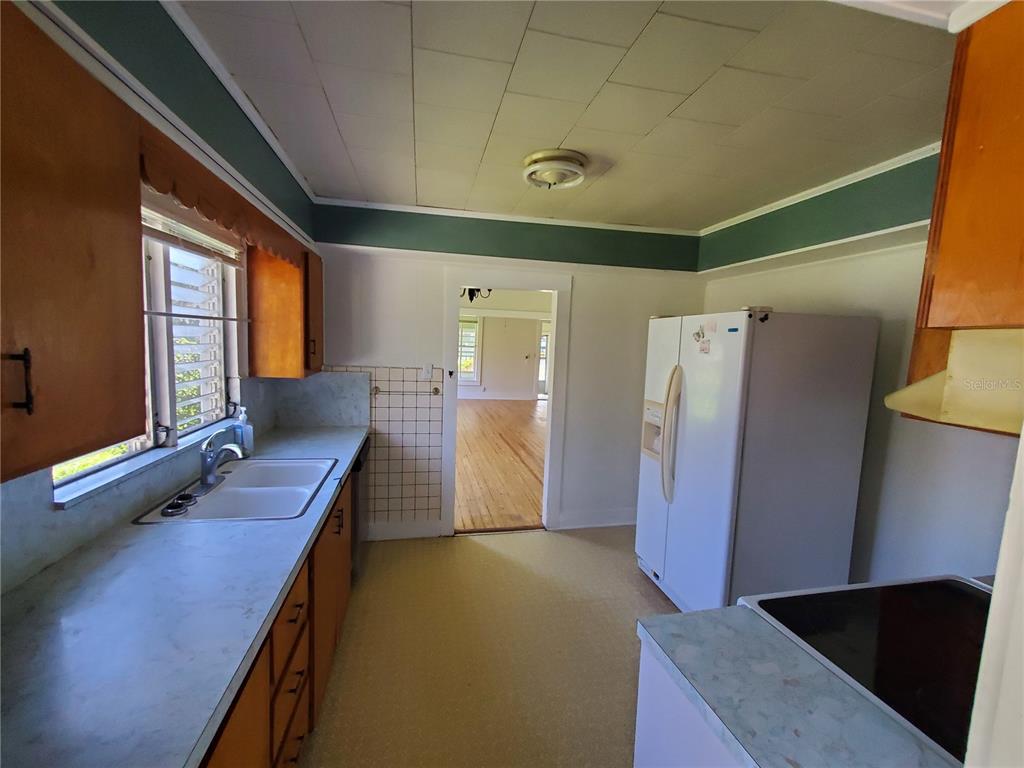A kitchen features wood cabinets, a white refrigerator, a double sink, and a tiled backsplash — 18670 NW 246TH STREET, HIGH SPRINGS, FL