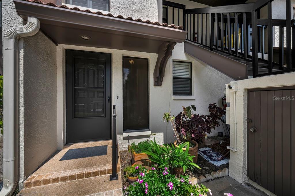 A front entryway features a dark door, a small window, and a potted plant garden — 3505 TARPON WOODS BOULEVARD UNIT O-403, PALM HARBOR, FL