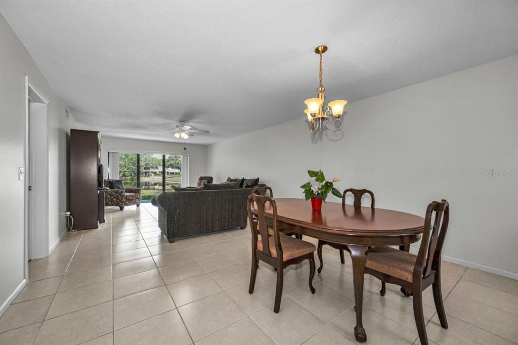 A dining area with a wooden table and chairs sits adjacent to a living room — 3505 TARPON WOODS BOULEVARD UNIT O-403, PALM HARBOR, FL