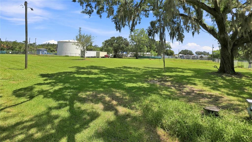 A large, grassy lot features a prominent oak tree and a distant water storage tank — 14125 PLUM LANE, HUDSON, FL
