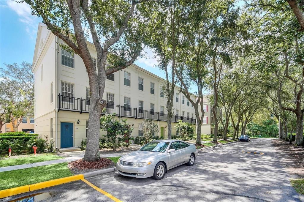 A multi-story townhouse exterior with a silver car parked on the street in front — 1007 SIENA PARK BOULEVARD E, KISSIMMEE, FL