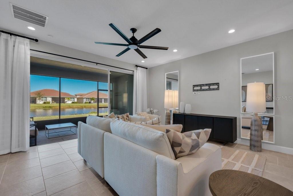 A living room features a white sectional sofa, a black console, and sliding glass doors — 4922 SIENNA ISLES AVENUE, WIMAUMA, FL