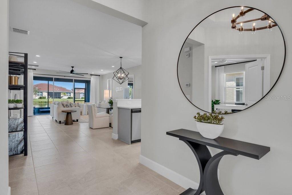 A foyer with a round mirror and console table looks into an open-concept living area — 4922 SIENNA ISLES AVENUE, WIMAUMA, FL