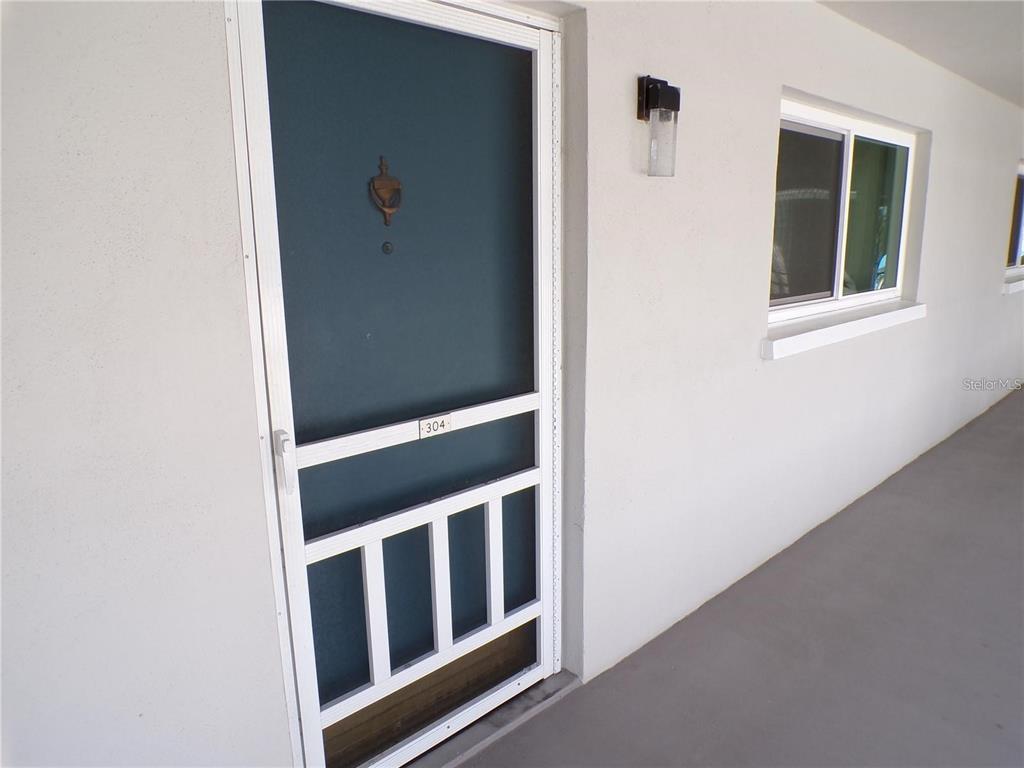 A white exterior wall features a dark screen door labeled 304 and a single window — 649 S TAMIAMI TRAIL S UNIT 304, VENICE, FL