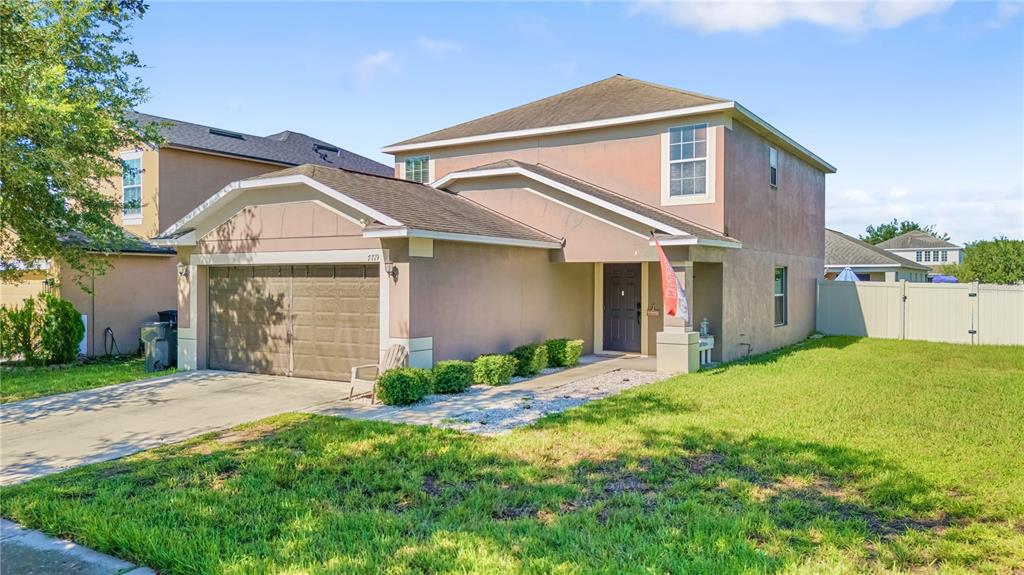 A two-story house with a tan stucco exterior, a two-car garage, and a front lawn — 7719 MAROON PEAK DRIVE, RUSKIN, FL