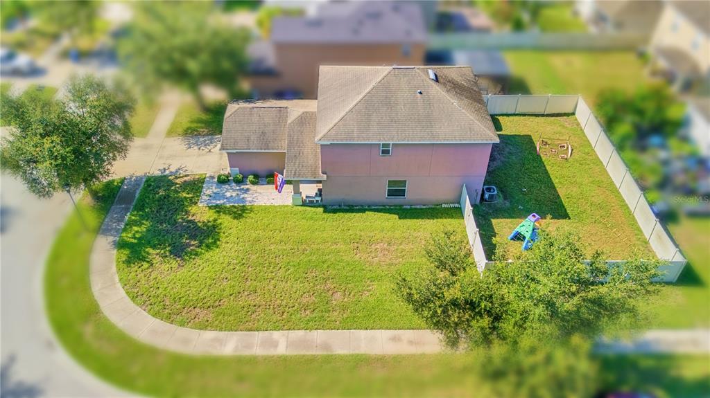 An aerial view of a two-story house with a fenced backyard and a corner lot — 7719 MAROON PEAK DRIVE, RUSKIN, FL