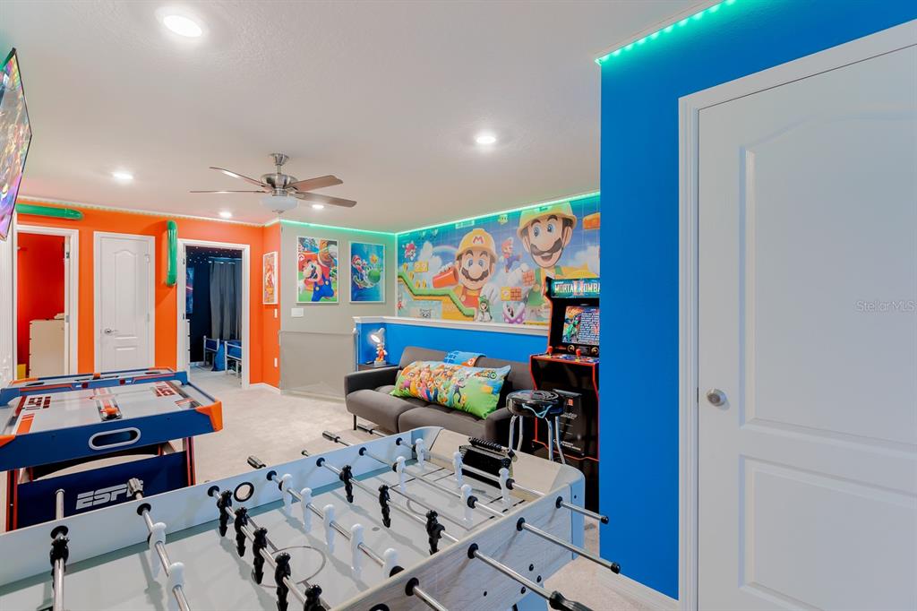 A game room features a foosball table, air hockey table, arcade cabinet, and Mario-themed wall mural — 7581 OAK SPRING LANE, DAVENPORT, FL