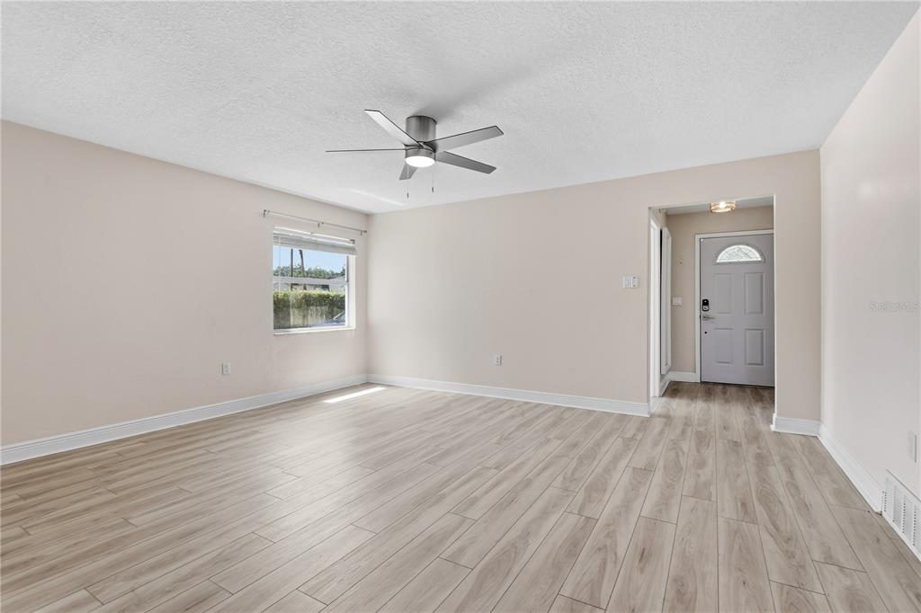 This virtually staged living room features light wood-look flooring, two sofas, and a patterned rug — 36 E WINTER PARK STREETS, ORLANDO, FL