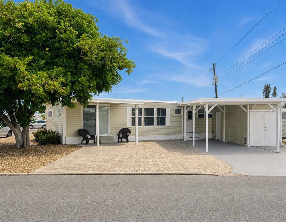 A single-story manufactured home features light siding, a paved patio, and an attached carport — 2203 MINNESOTA AVENUE, BRADENTON, FL