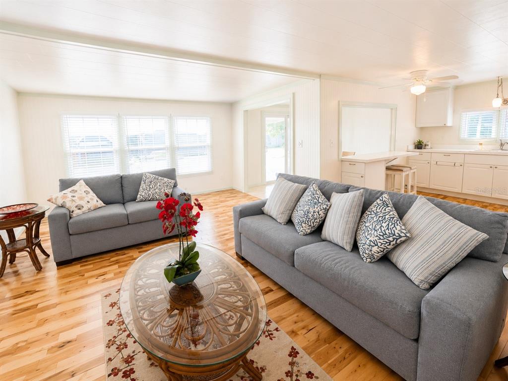 A living room features two gray sofas, a glass coffee table, and light wood flooring — 2203 MINNESOTA AVENUE, BRADENTON, FL