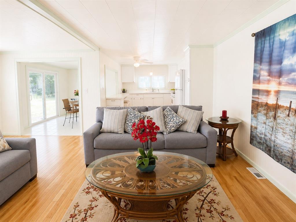 A living room with a grey sofa, glass-topped rattan coffee table, and hardwood floors — 2203 MINNESOTA AVENUE, BRADENTON, FL