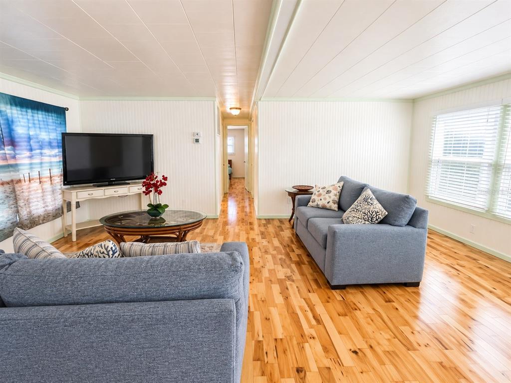 A living room features blue sofas, a glass-topped coffee table, and light wood flooring — 2203 MINNESOTA AVENUE, BRADENTON, FL