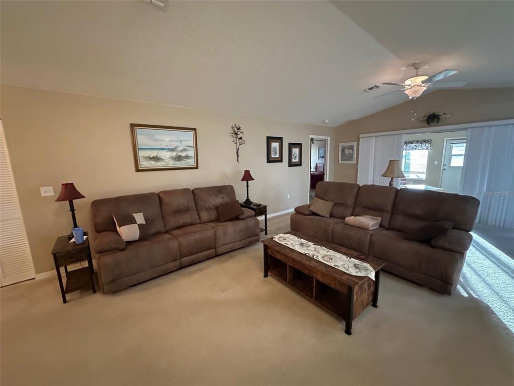 A living room features two brown sofas, a wooden coffee table, and beige carpeting — 32905 TIMBERWOOD DRIVE, LEESBURG, FL