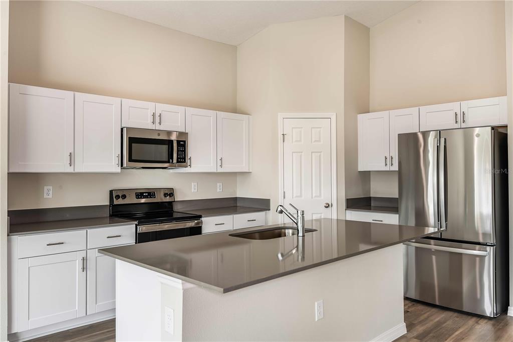 A kitchen features white cabinets, stainless steel appliances, a center island, and gray countertops — 1362 PALMEROY ROAD, HAINES CITY, FL