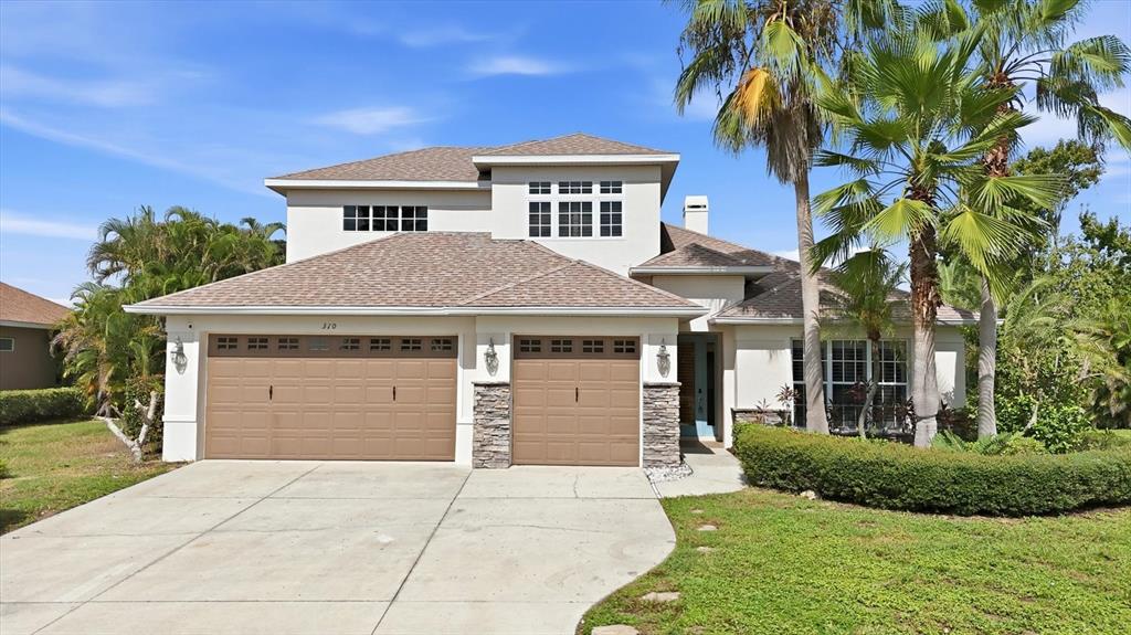 A two-story house with a three-car garage, stone accents, and palm trees in the front yard — 310 SALVIA COURT, BRADENTON, FL