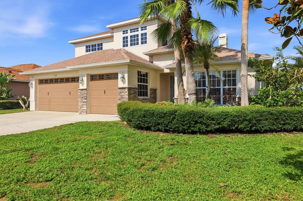 A two-story suburban house with a two-car garage, stone accents, and a manicured front hedge — 310 SALVIA COURT, BRADENTON, FL