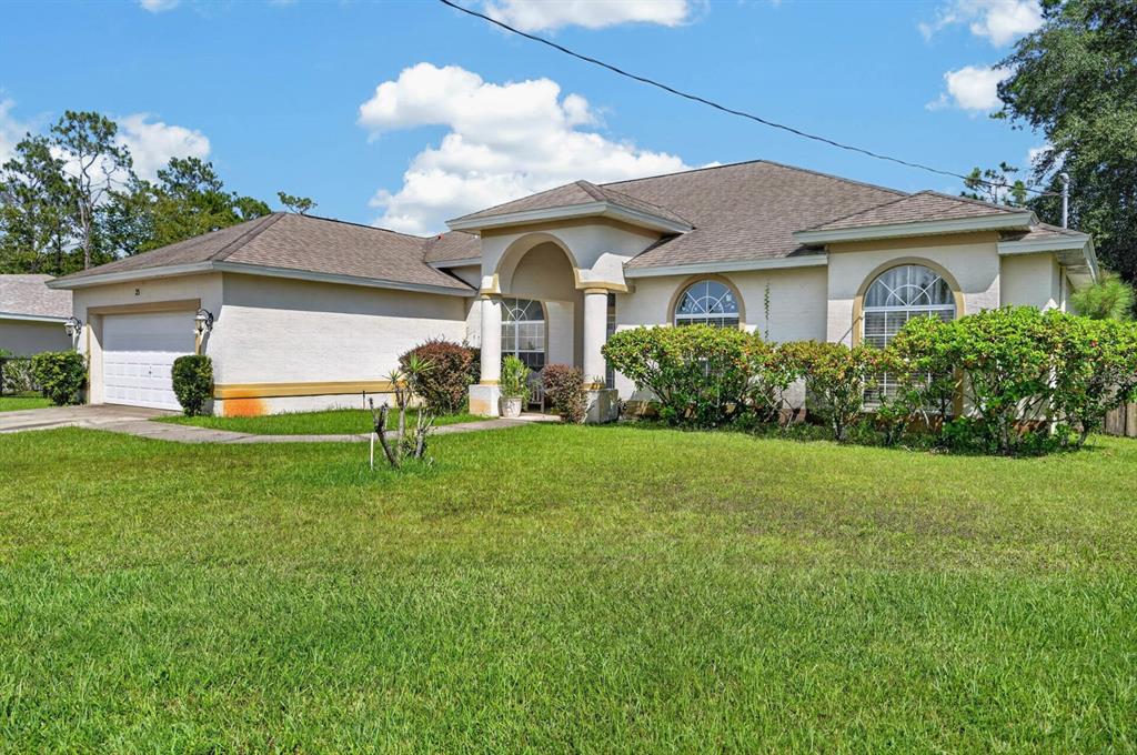 A single-story house with a beige stucco exterior, arched entryway, and a two-car garage — 25 KATHRYN PLACE, PALM COAST, FL