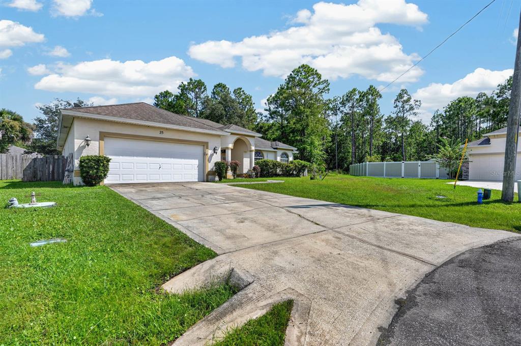 A single-story house with a two-car garage and a concrete driveway sits on a lawn — 25 KATHRYN PLACE, PALM COAST, FL