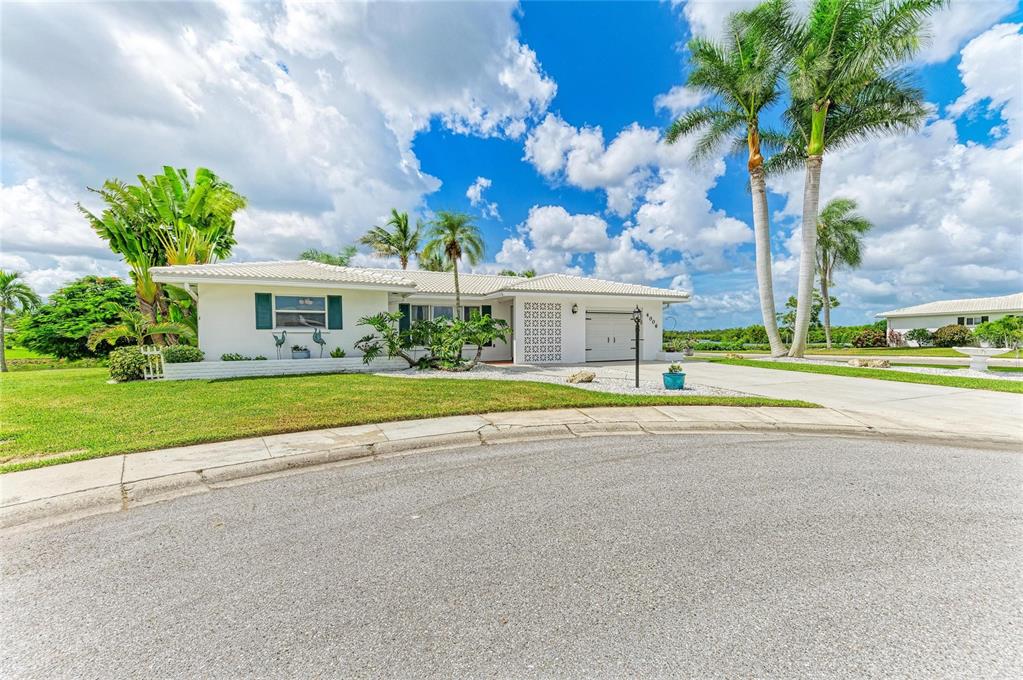 A white single-story house with a tile roof, palm trees, and a paved driveway — 4006 JOYCE DRIVE, BRADENTON, FL