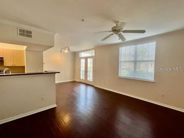 An open-concept living room features dark wood flooring, a ceiling fan, and glass balcony doors — 770 SIENA PALM DRIVE UNIT 207, CELEBRATION, FL
