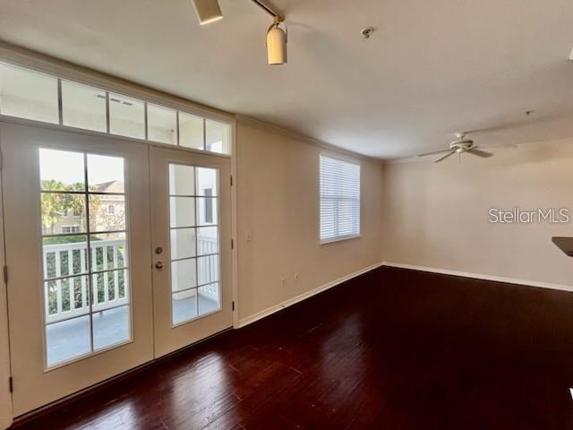An empty room with dark hardwood floors, a ceiling fan, and glass doors to a balcony — 770 SIENA PALM DRIVE UNIT 207, CELEBRATION, FL
