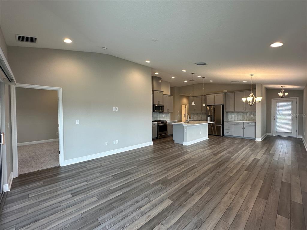An open-concept kitchen and living area features wood-look flooring, gray cabinetry, and a kitchen island — 12533 OAK HILL WAY, PARRISH, FL