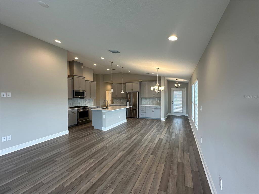 An open-concept kitchen features gray cabinetry, stainless steel appliances, a center island, and wood flooring — 12533 OAK HILL WAY, PARRISH, FL