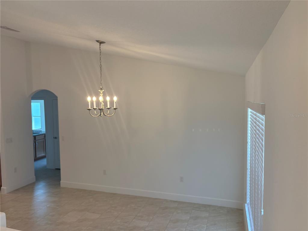 A dining area with a chandelier, vaulted ceiling, tile flooring, and an arched doorway — 53 ERIC DRIVE, PALM COAST, FL
