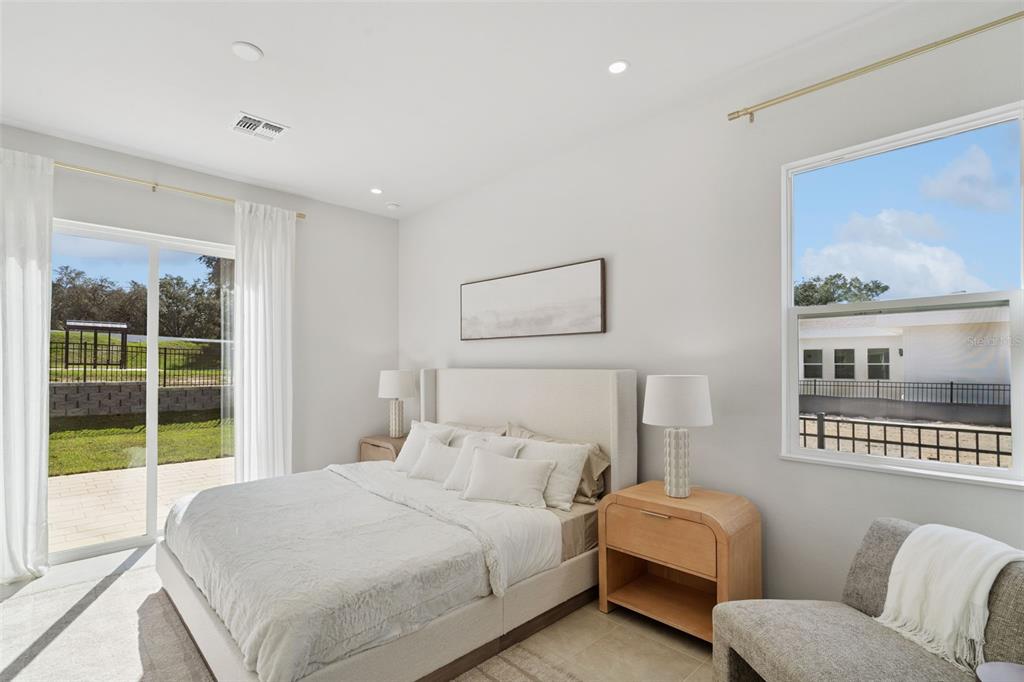 A bedroom features a bed, two nightstands, a chair, and a sliding glass door to outside — 419 SKYFIELD COURT, LADY LAKE, FL