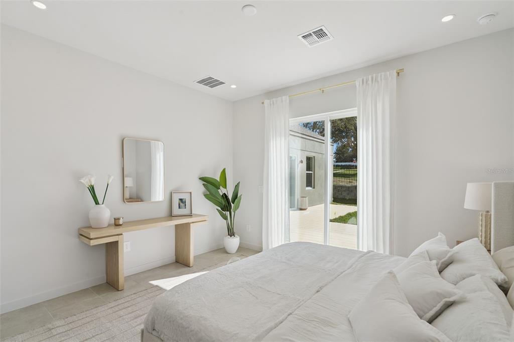 A bedroom features a light wood console table, a potted plant, and a sliding glass door — 419 SKYFIELD COURT, LADY LAKE, FL