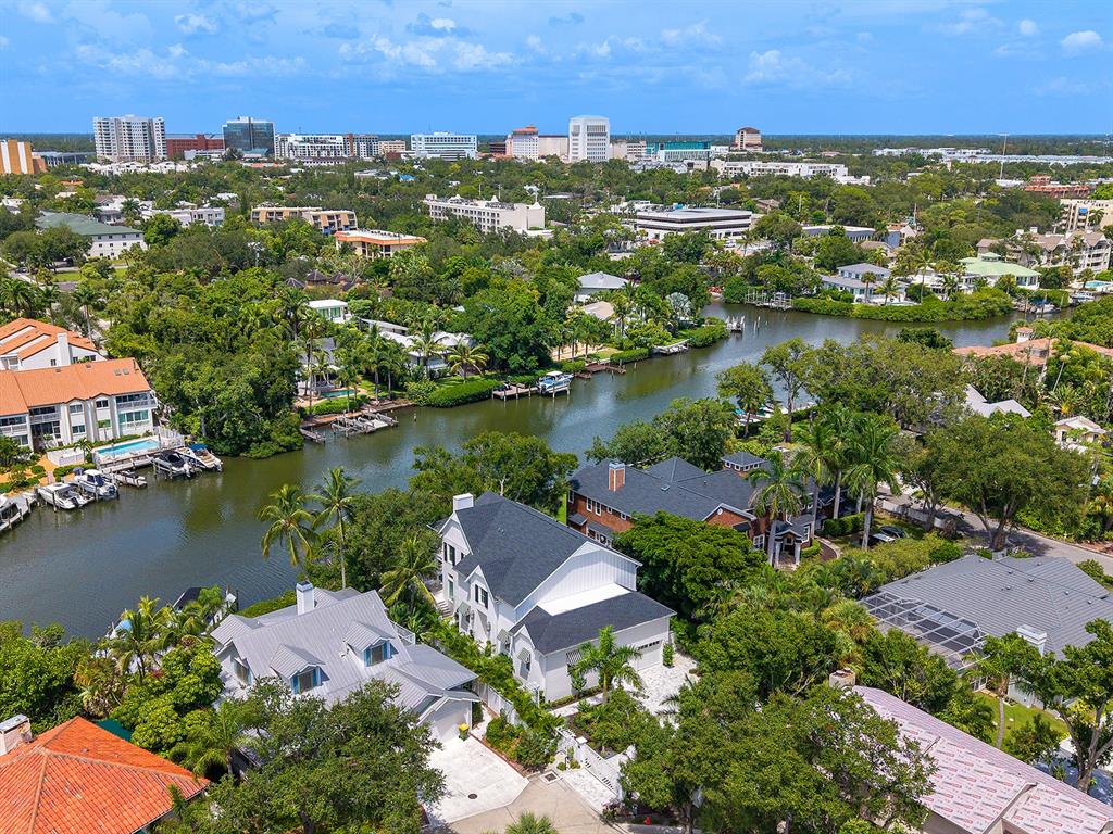 An aerial view of waterfront homes with private docks along a canal near a city — 1621 BAY POINT COURT, SARASOTA, FL